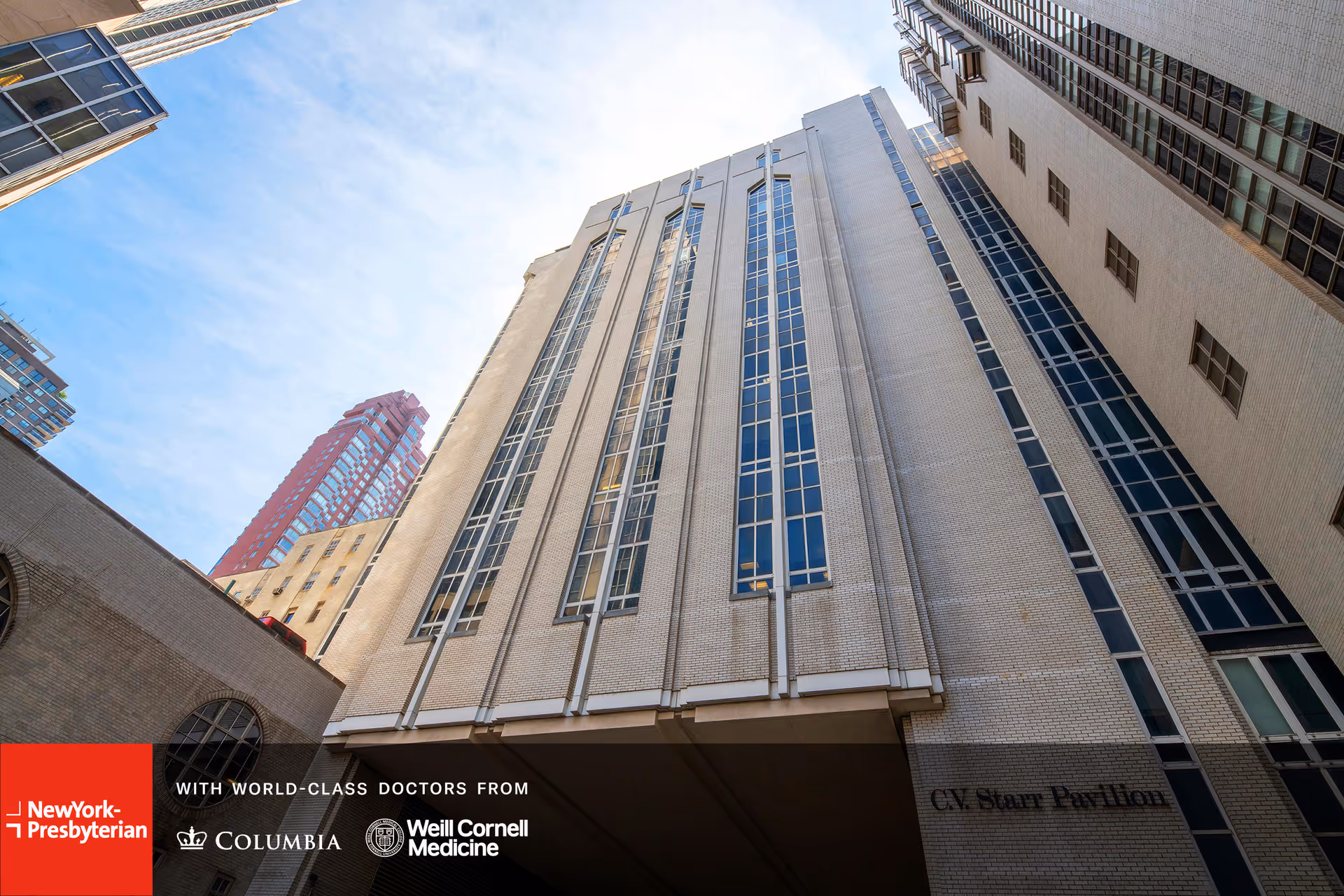 Low-angle exterior view of a tall medical building with blue sky.