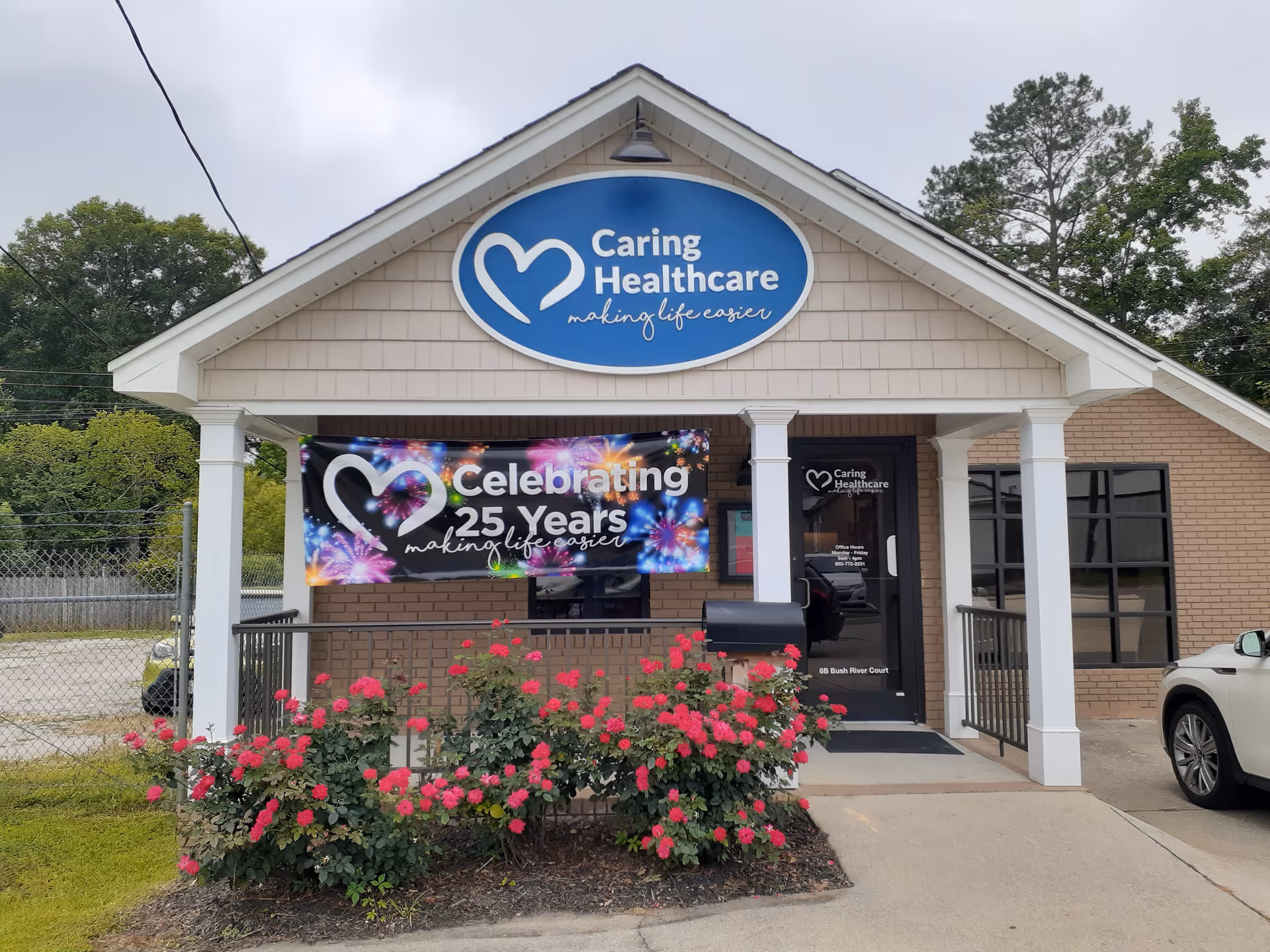 Front view of Caring Healthcare facility with banner, porch, and pink roses.