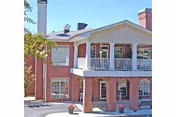 Brick two-story building with white columns, a covered front porch, and a second-floor balcony.