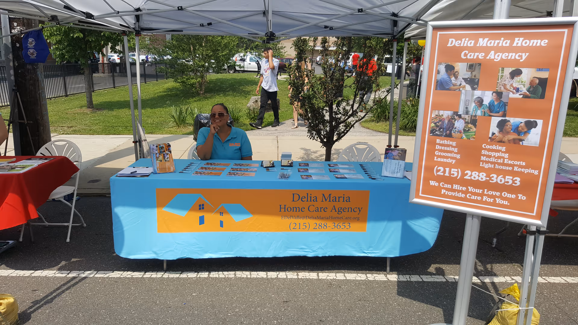 Delia Maria Home Care Agency booth under a canopy with a representative at a table.