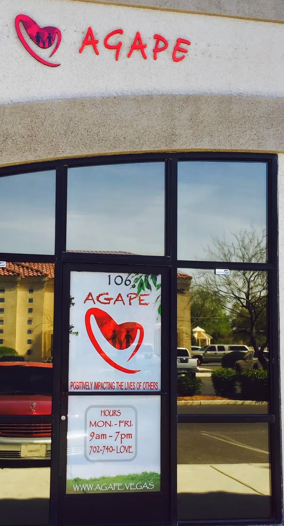 Facade of AGAPE senior living center with glass doors and sign.