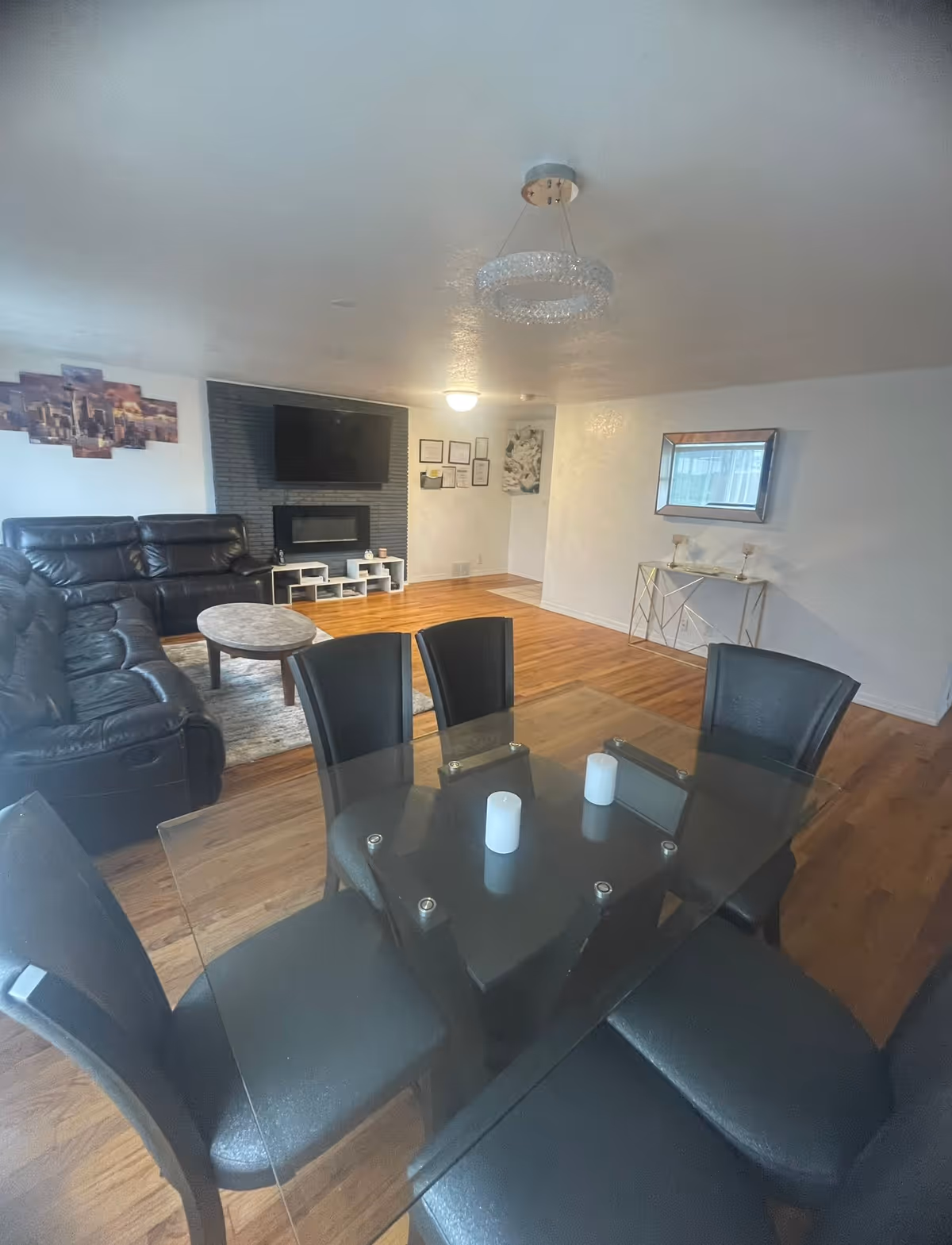 Spacious living and dining area with glass dining table, black leather seating, and a TV.