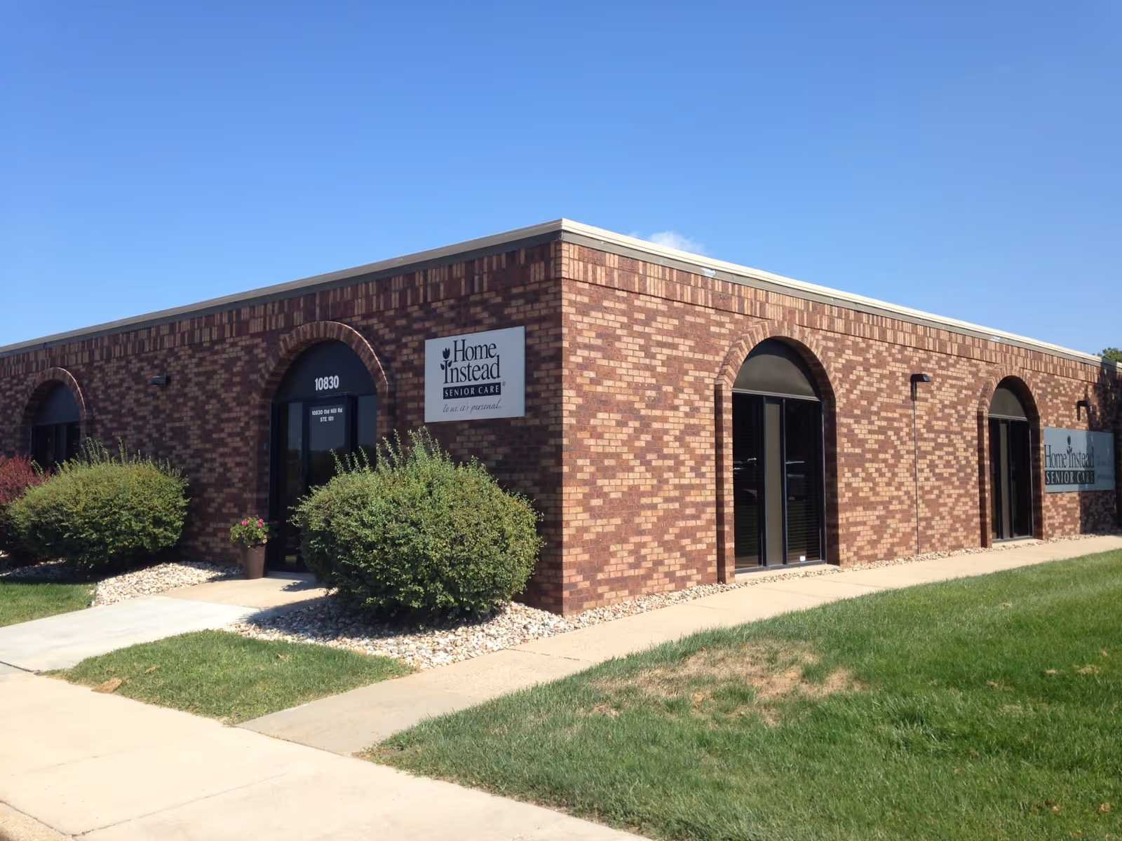 Brick building with arched entrances and Home Instead Senior Care sign.