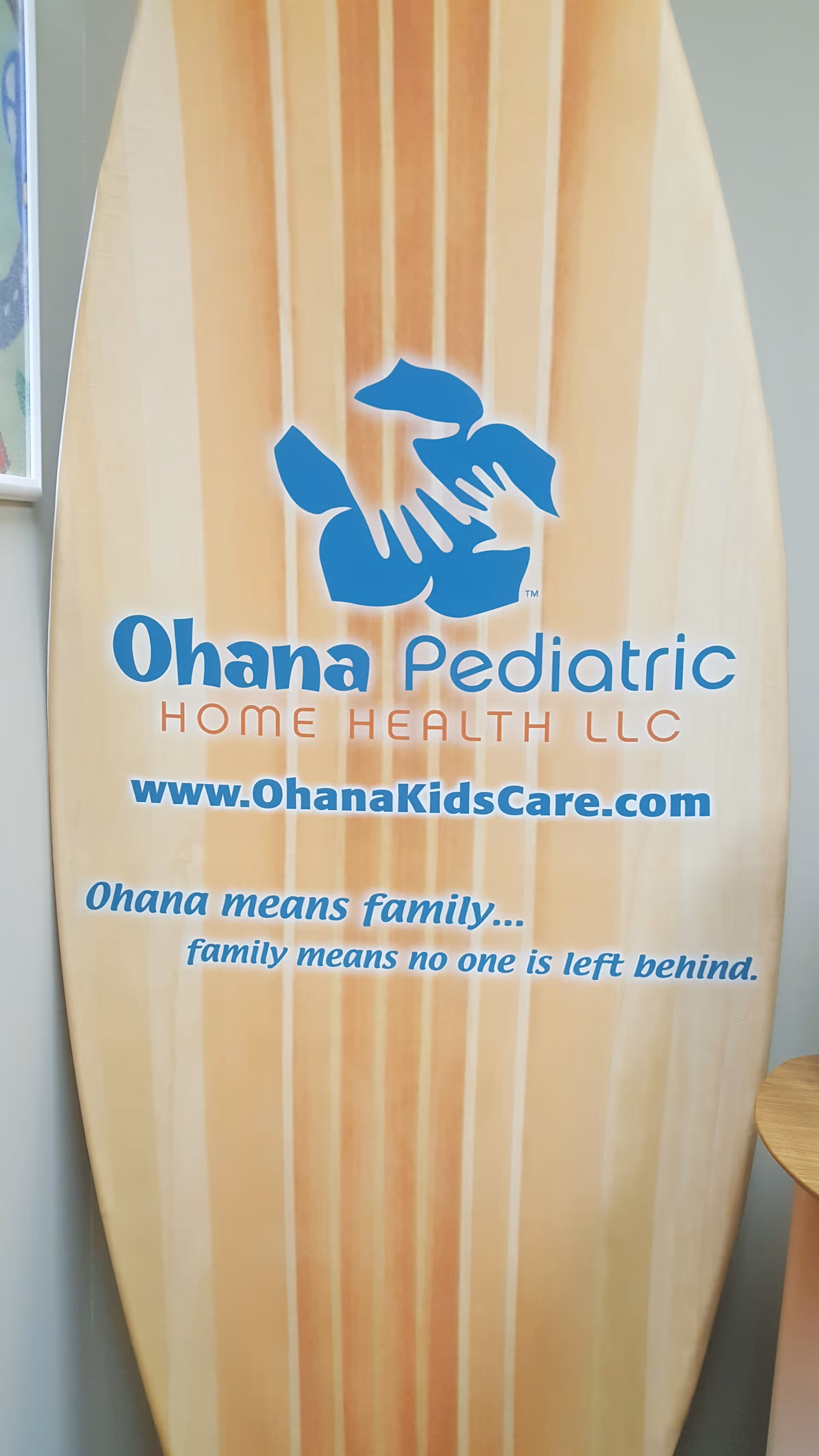 Inside view of a surfboard-shaped sign for Ohana Pediatric Home Health LLC with logo and website.