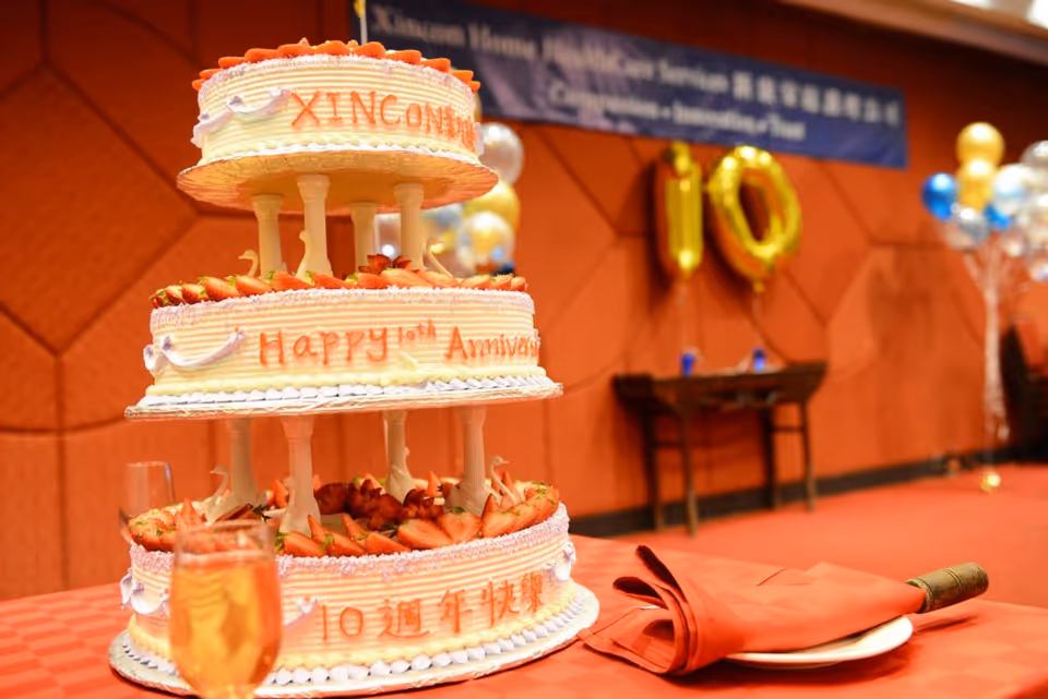 A large multi-tier cake on a red table in an indoor celebration hall.