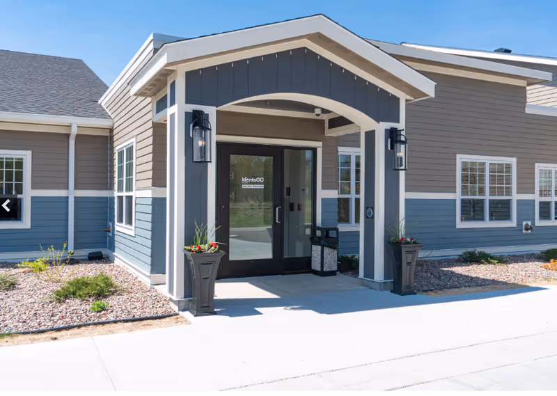 Front entrance of Elysian Senior Homes of Duluth, glass doors with arched canopy and planters.