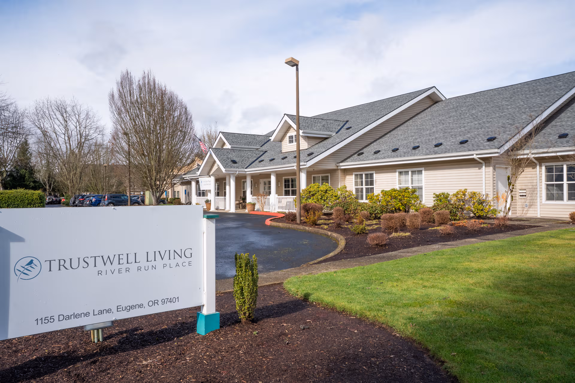 Exterior view of Trustwell Living at River Run Place with sign and landscaped entrance.