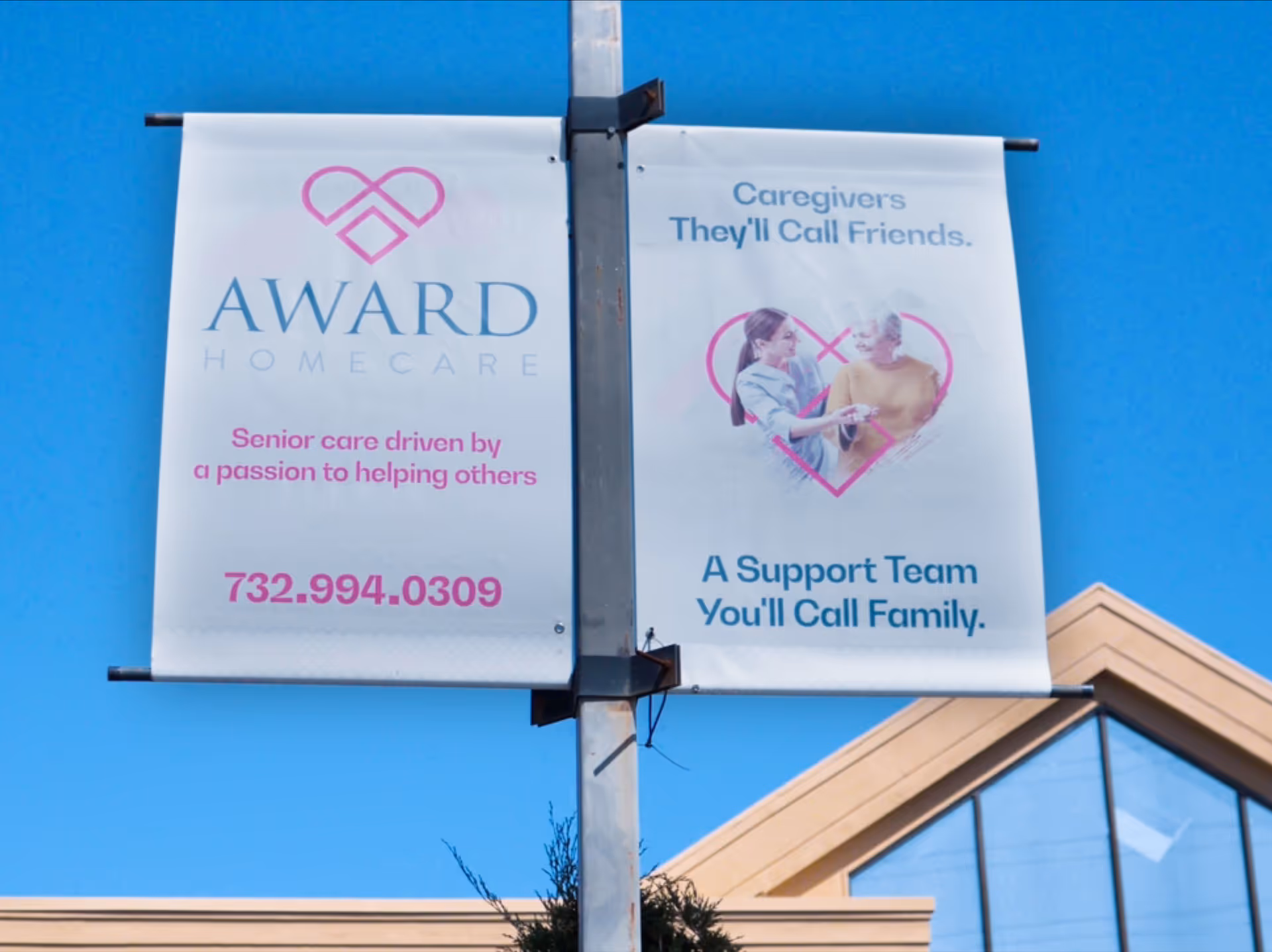 Two banners advertising Award HomeCare hang on a pole against a blue sky.