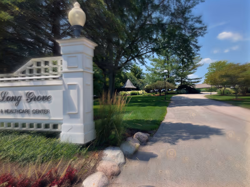 Exterior view of a white entrance sign reading Long Grove Health Care Center beside a driveway.