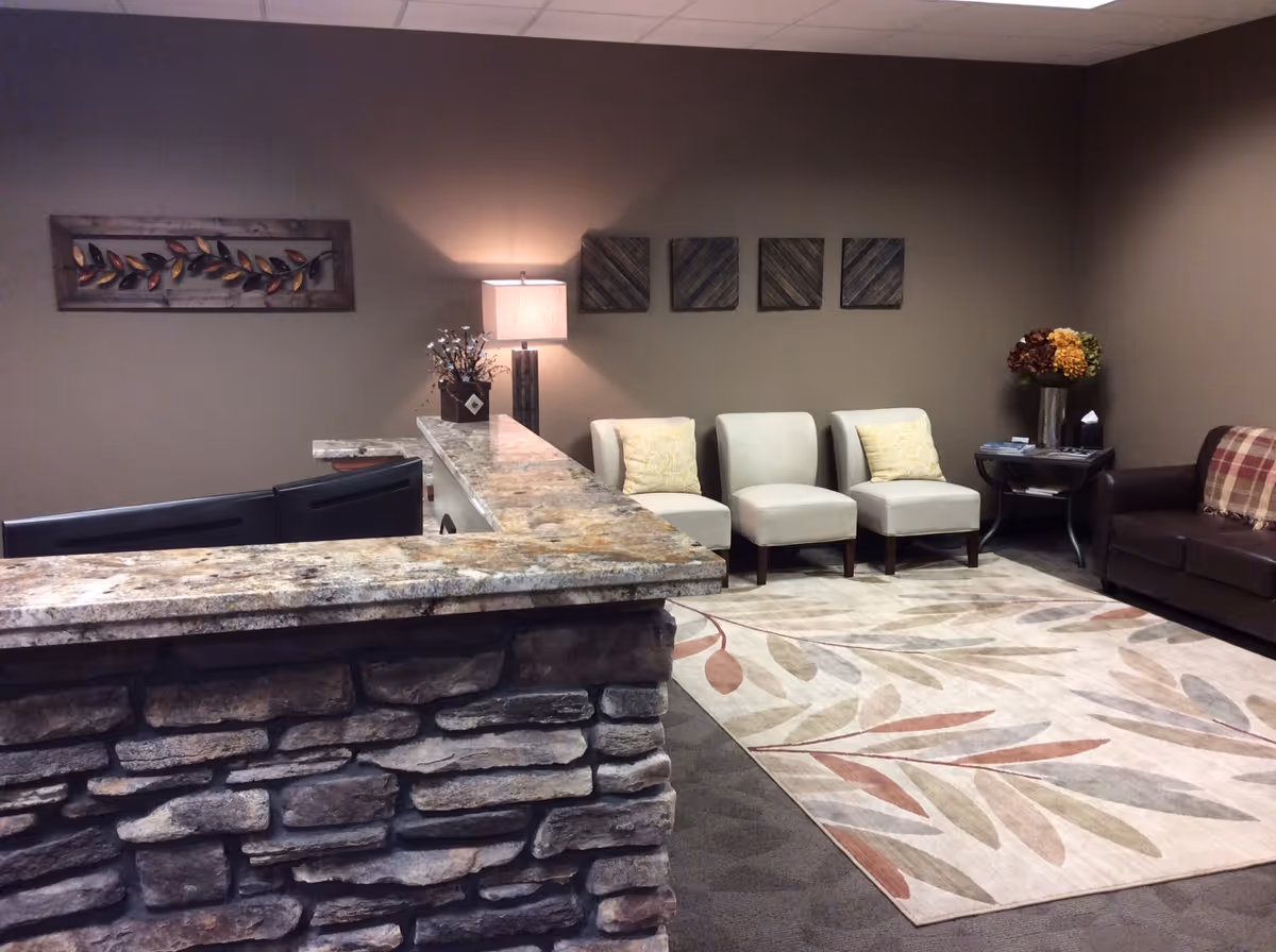 Stone-front reception desk with seating area in a beige, warmly lit lobby.