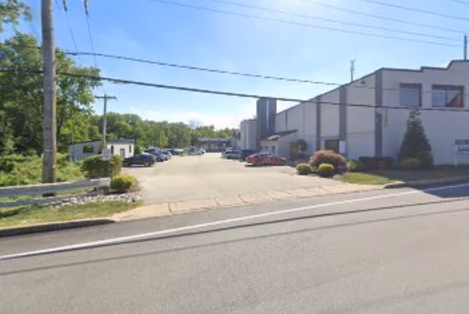 Exterior view of a facility building with a parking lot along a street.