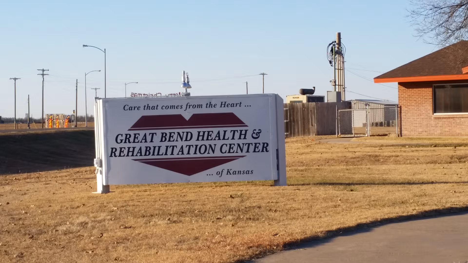 Exterior view of a sign for Great Bend Health & Rehabilitation Center beside a brick building.