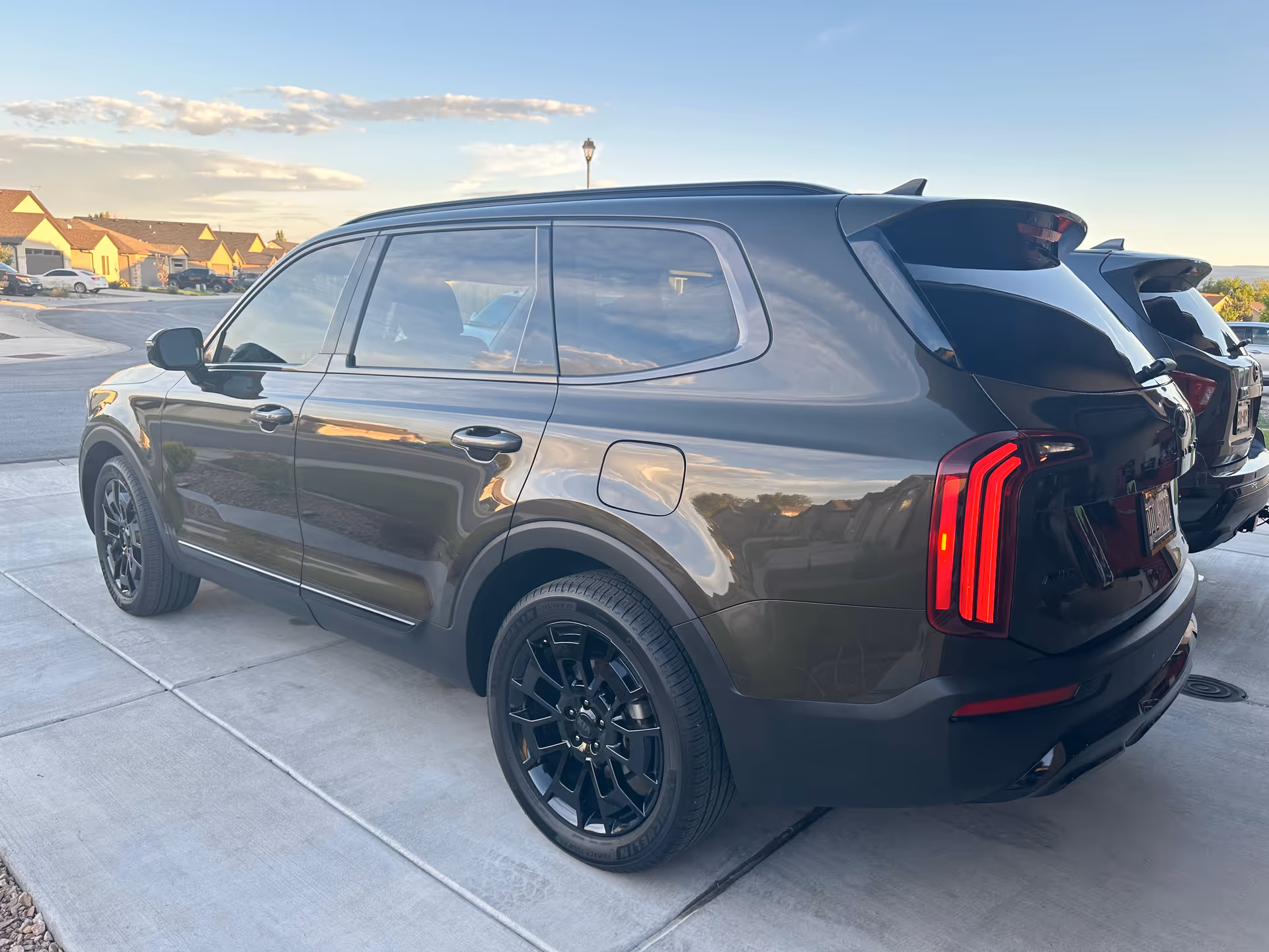 Black SUV parked on a driveway with suburban houses in the background.