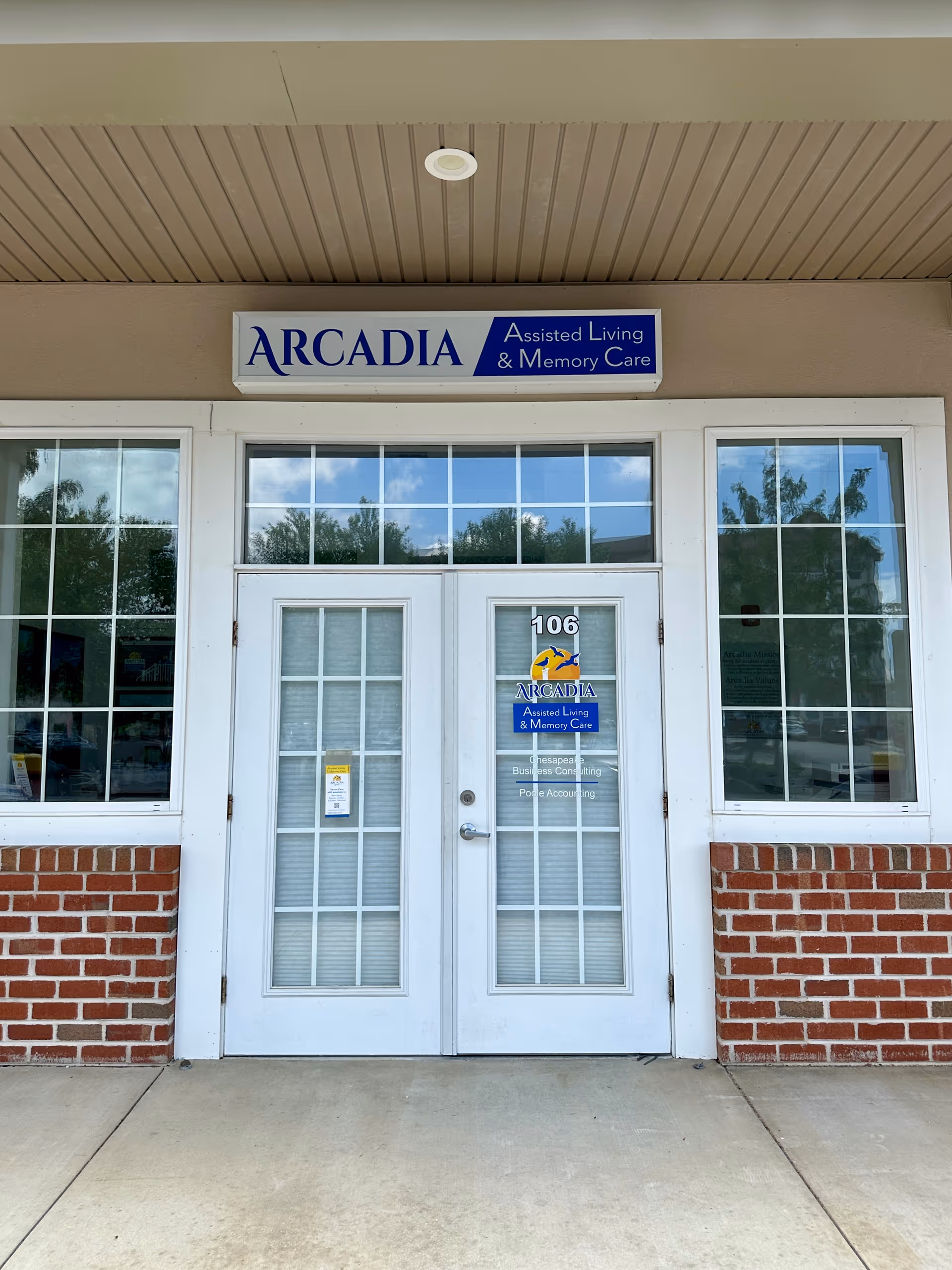 Exterior view of Arcadia Assisted Living entrance with white doors and brick siding.
