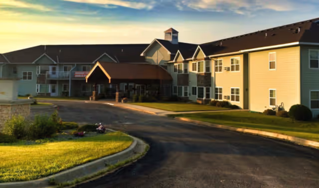 Arbor Garden Place exterior: a two-story senior living facility with curved driveway and entrance.