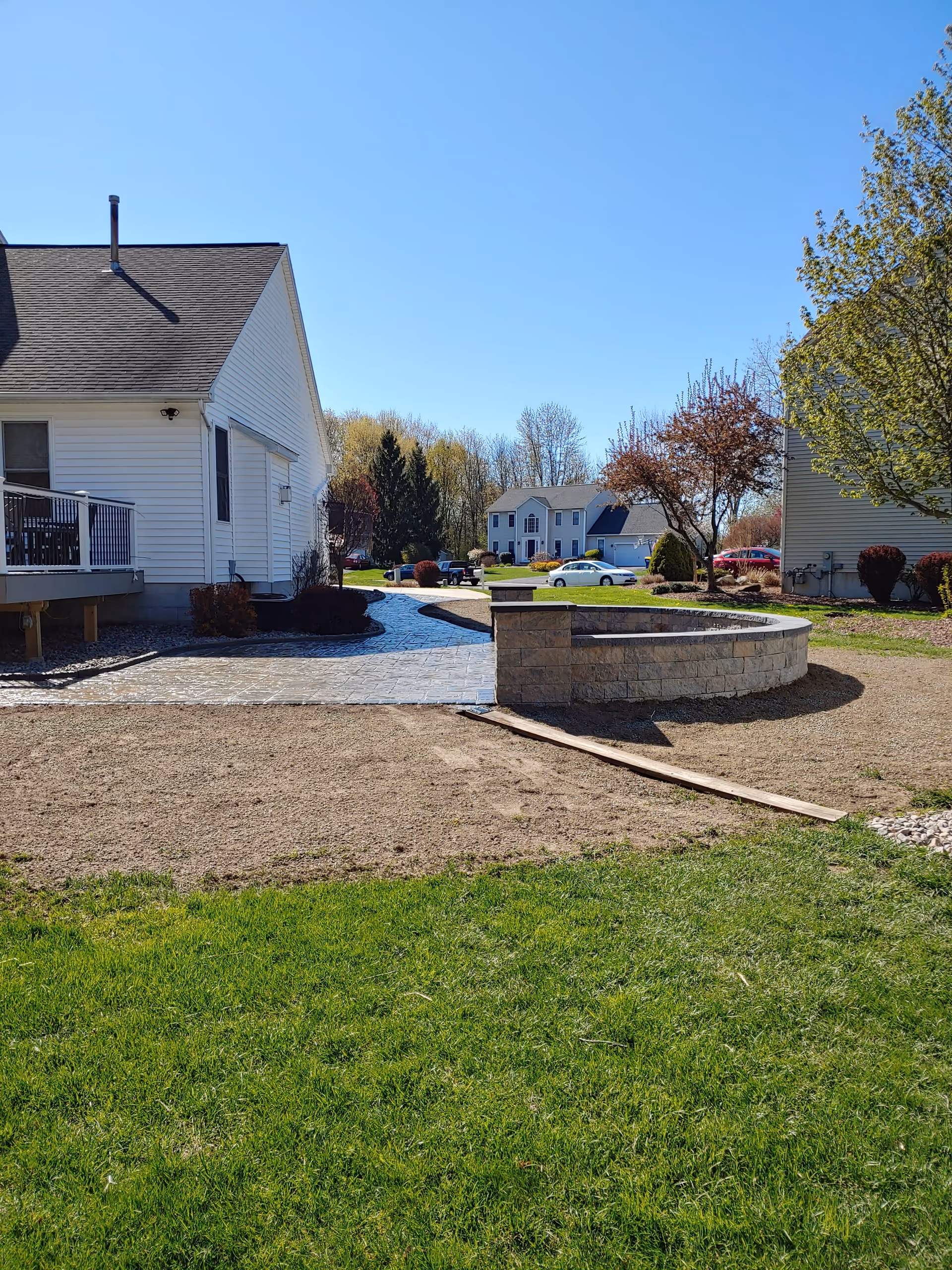 Outdoor courtyard with white residential buildings, a circular stone seating area, and green lawn.