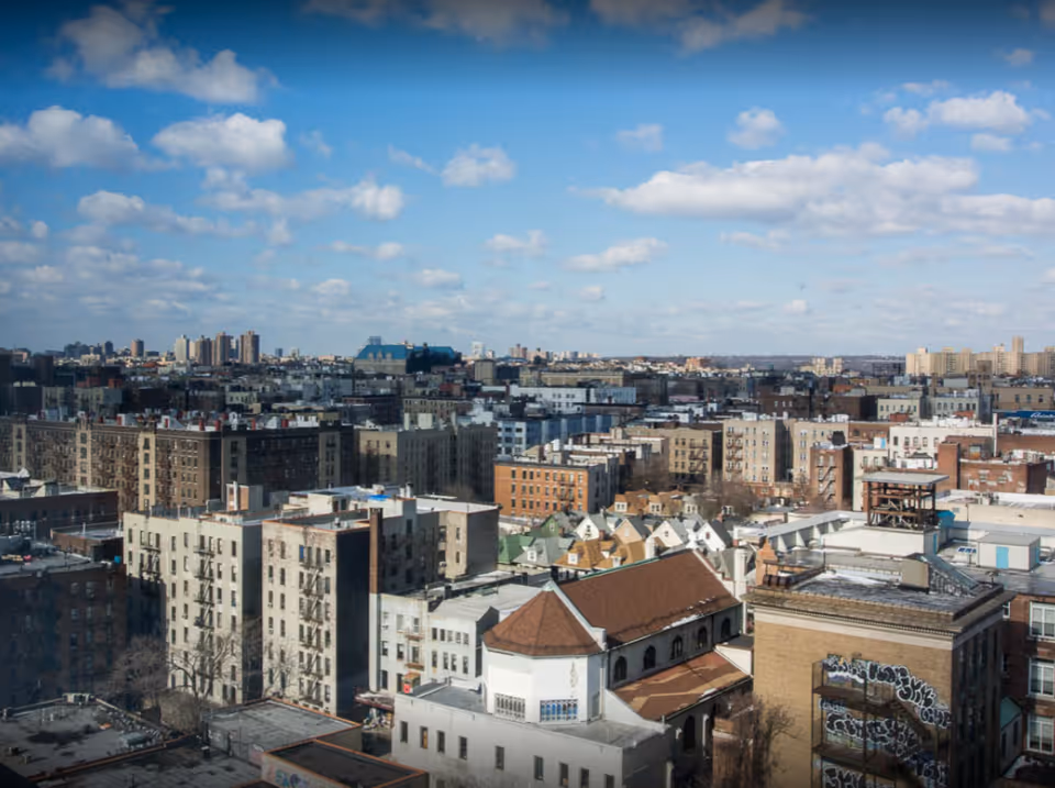 Rooftops and buildings form a cityscape beneath a blue sky.