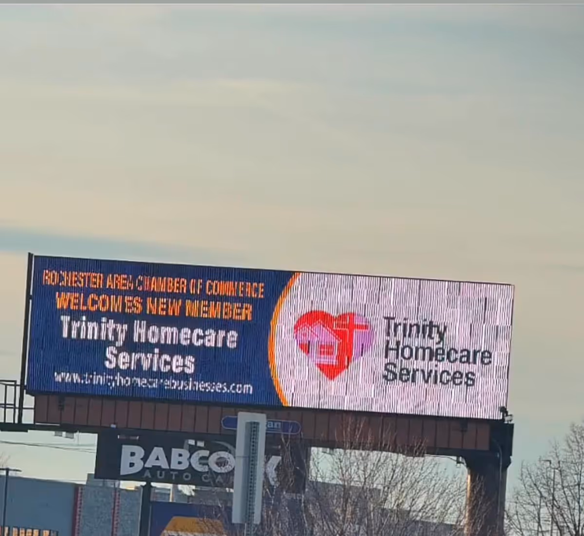A large outdoor billboard on a highway advertising Trinity Homecare Services and its heart logo.