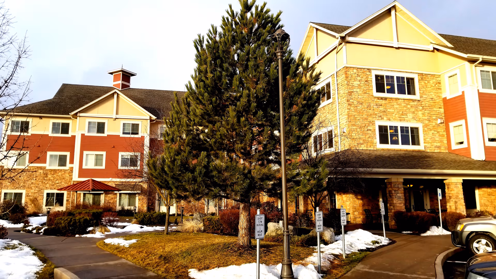 Exterior view of Garden Plaza of Post Falls building with stone accents, trees, and parking.