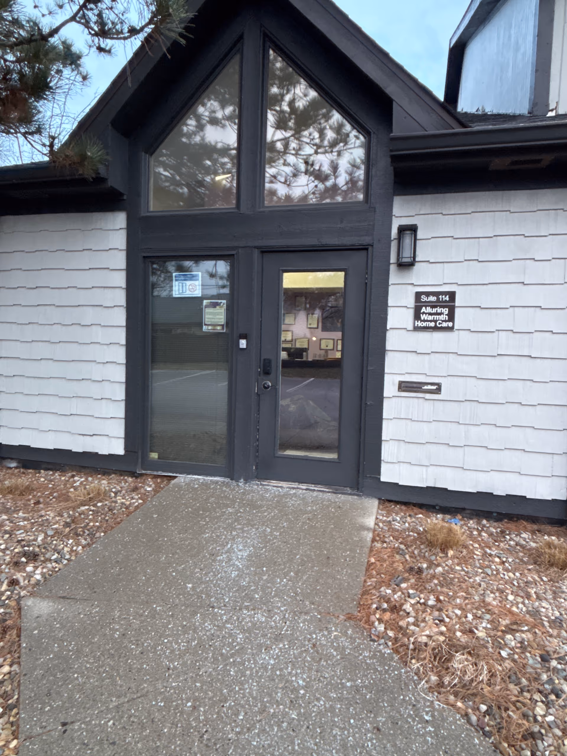 Entrance to Alluring Warmth Home Care LLC building with glass door and triangular window.