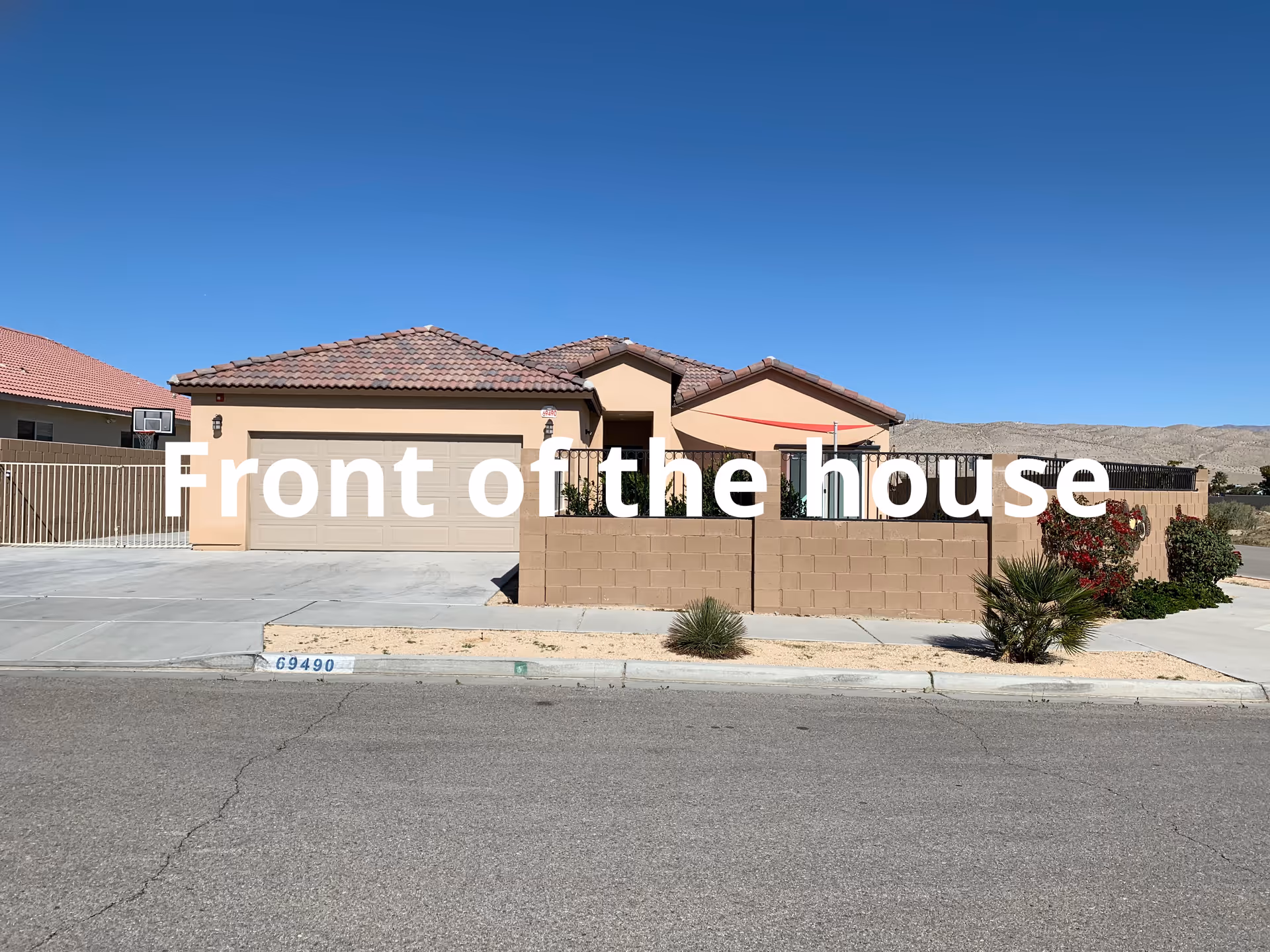 Front view of a tan retirement home with a gated driveway under a clear blue sky.