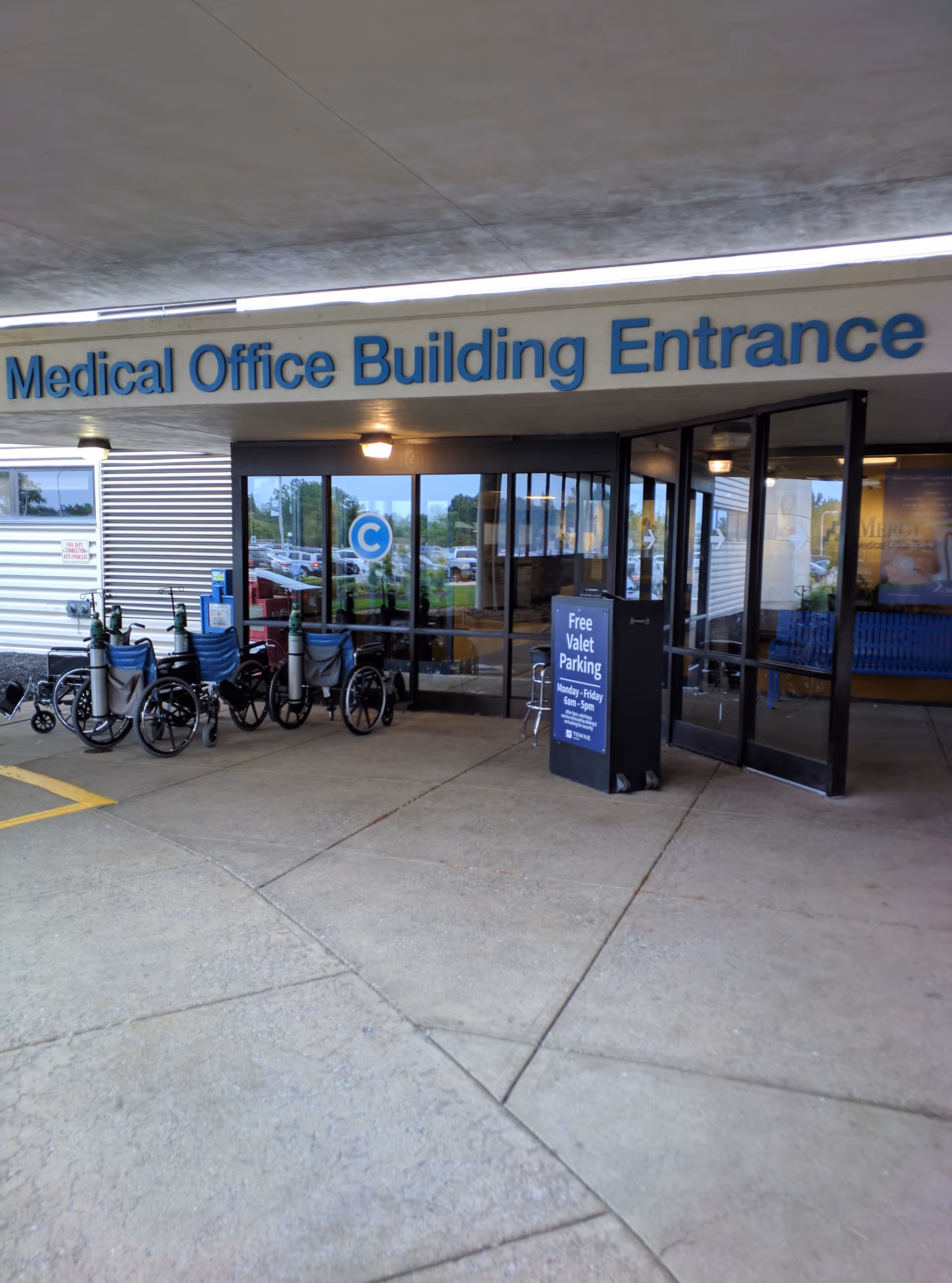 Exterior view of Mercy Health Lorain Hospital entrance with wheelchairs and a valet parking sign.