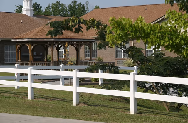 Exterior view of Croatan Village with a white fence and wooden gazebo in a green yard.
