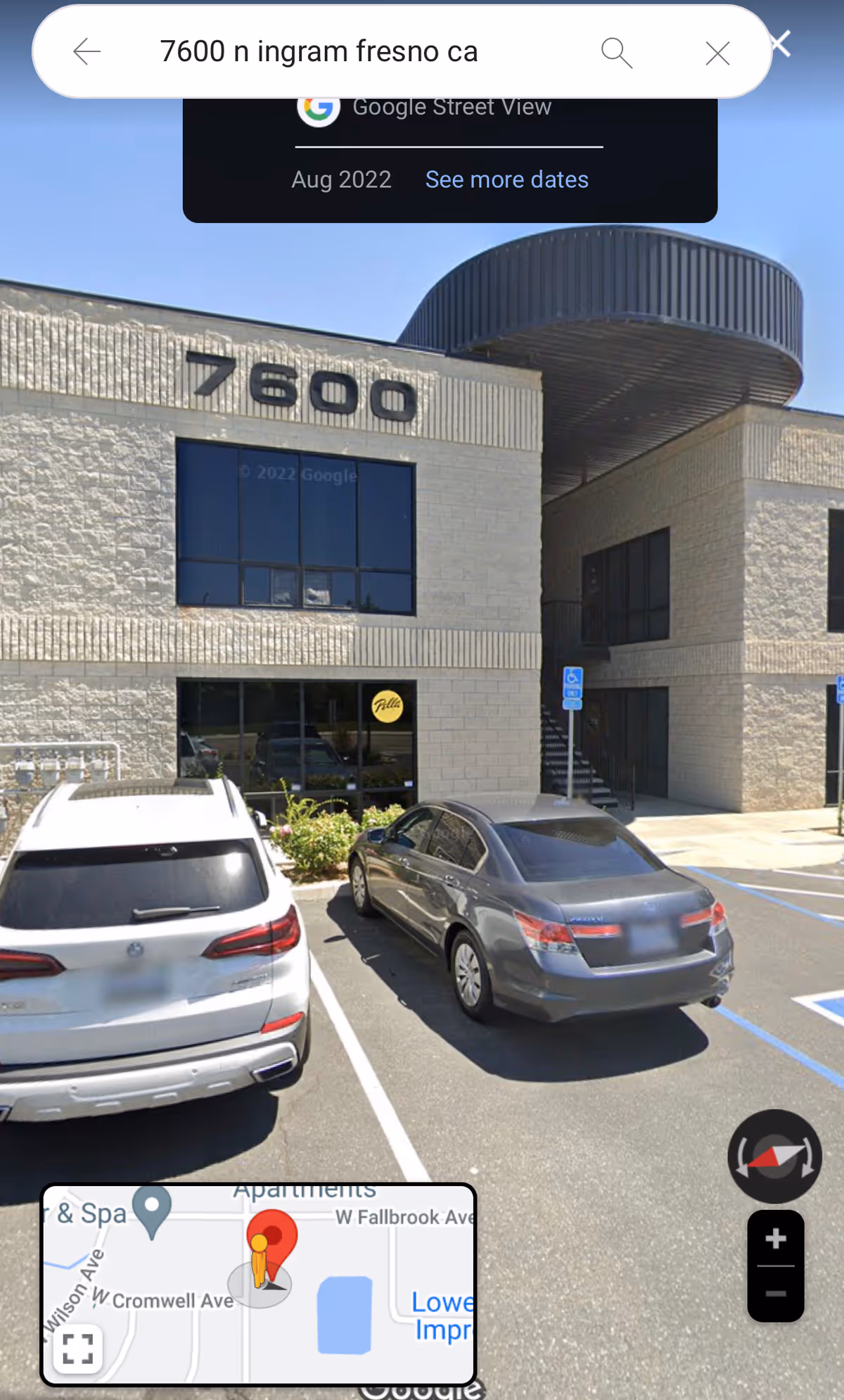 Front exterior of a beige brick building at 7600 with parked cars.