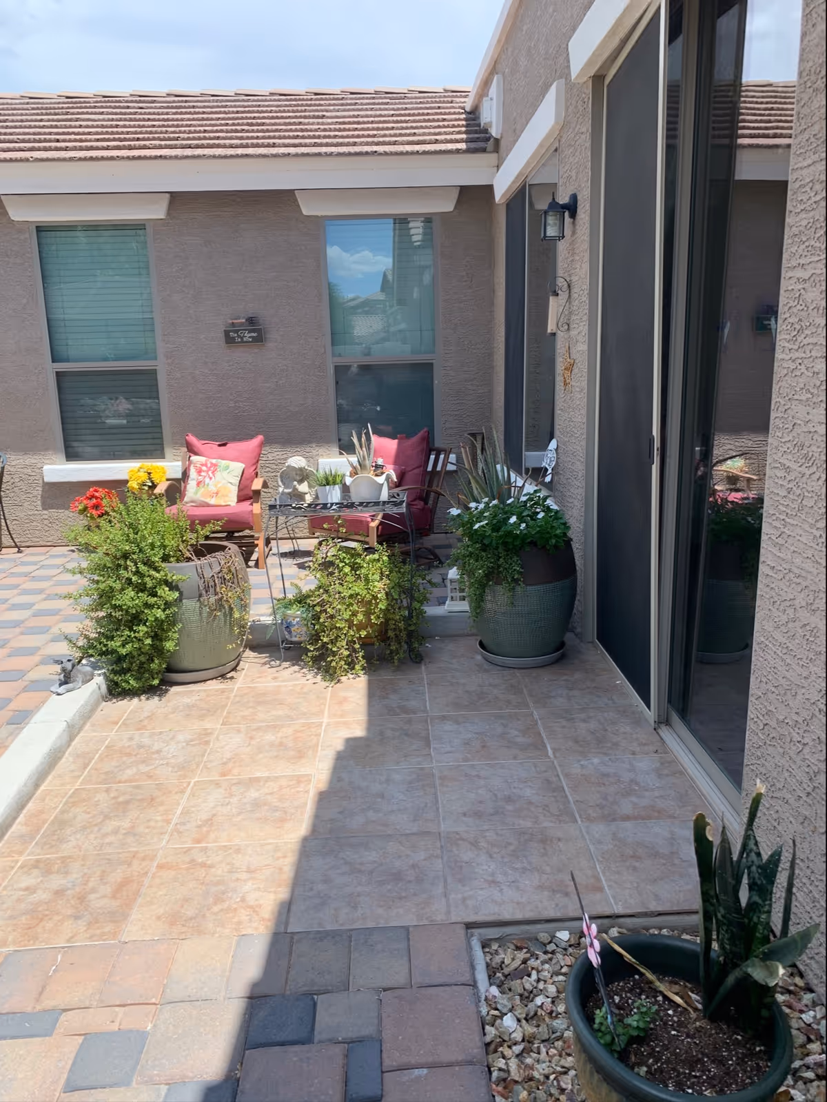 Meridian ALH outdoor patio with chairs, plants, and potted decor beside sliding glass doors.