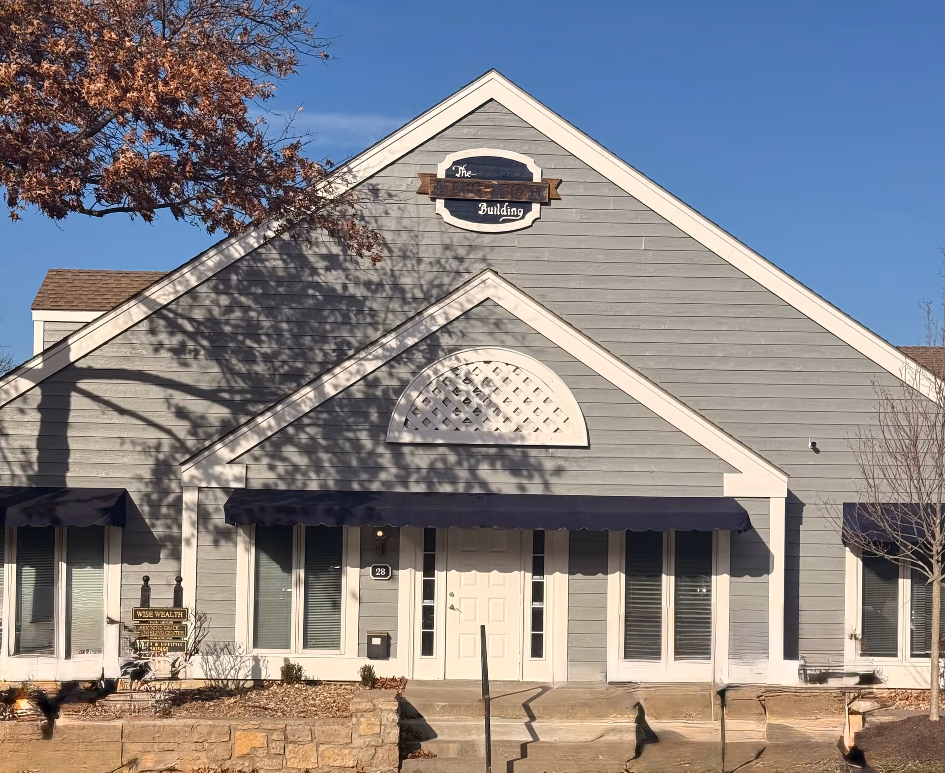 Front exterior of a gray senior living building with awnings and entry steps.