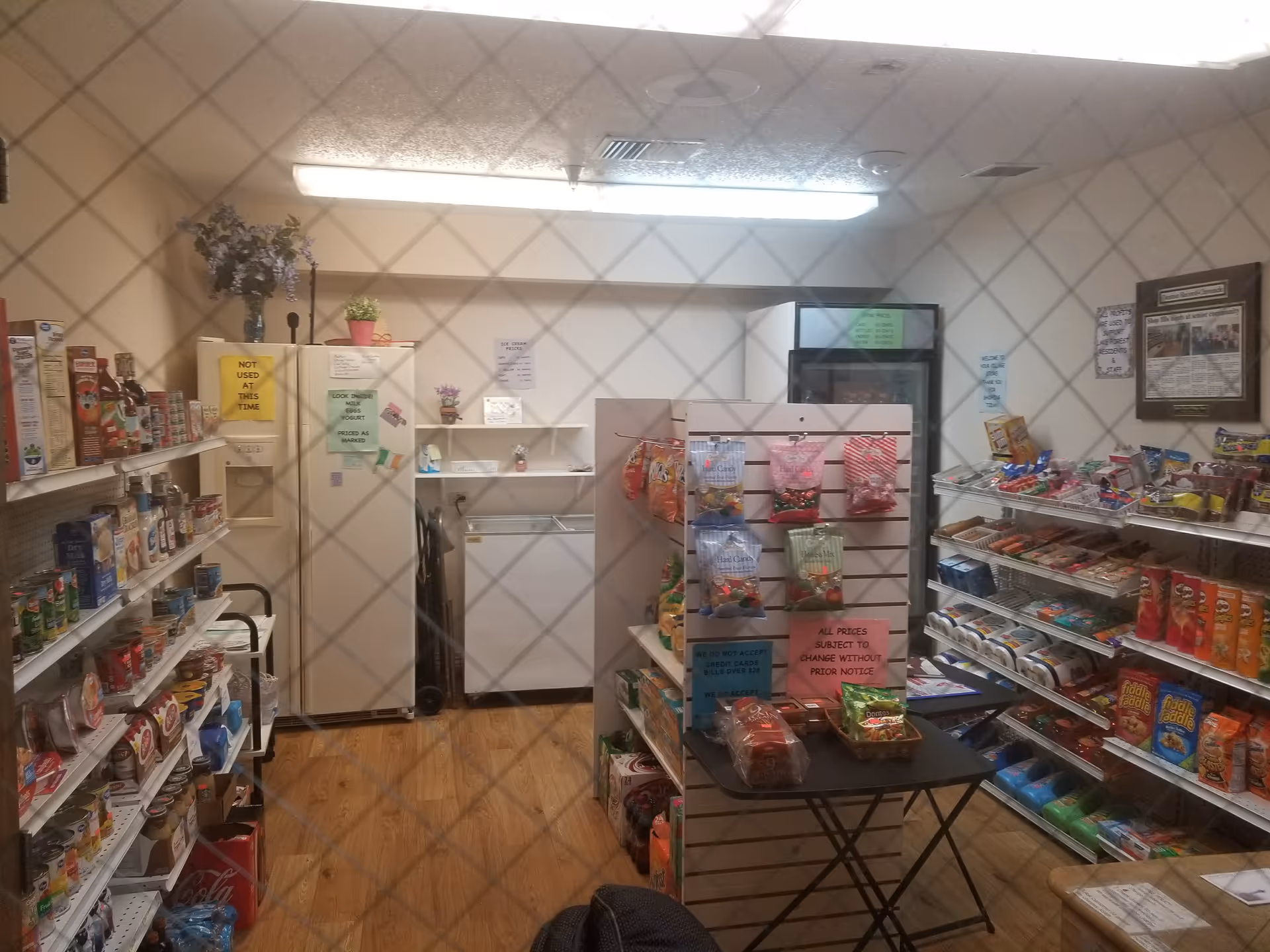 Indoor convenience shop in a senior facility with snack shelves, a display table, and a fridge.