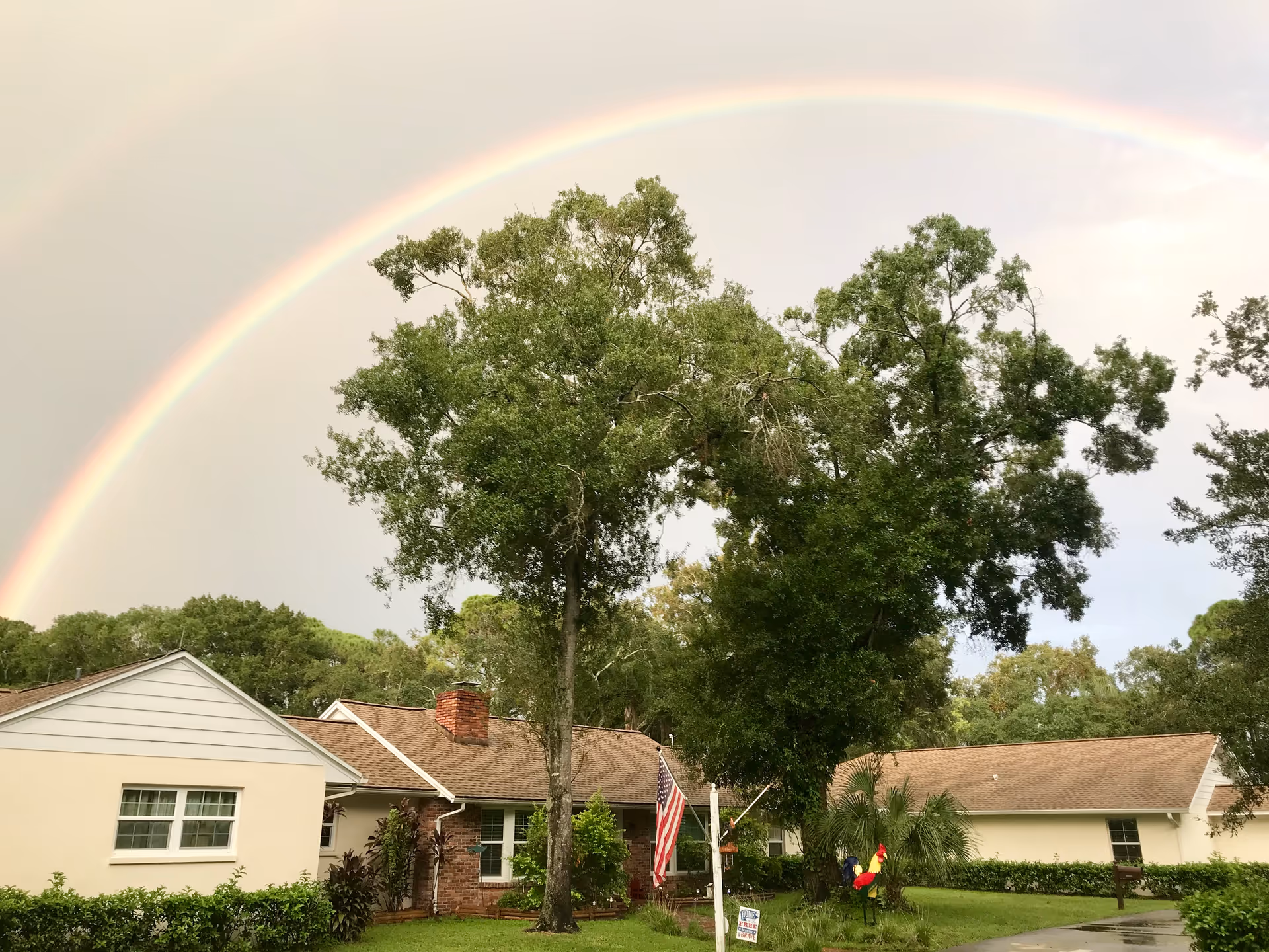 Front view of a single-story assisted living facility with a rainbow over trees