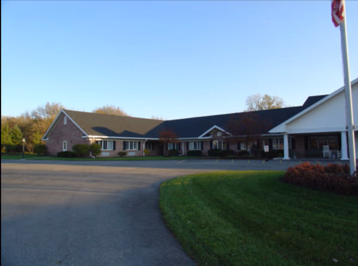 Exterior view of a single-story brick senior living facility with a parking lot.