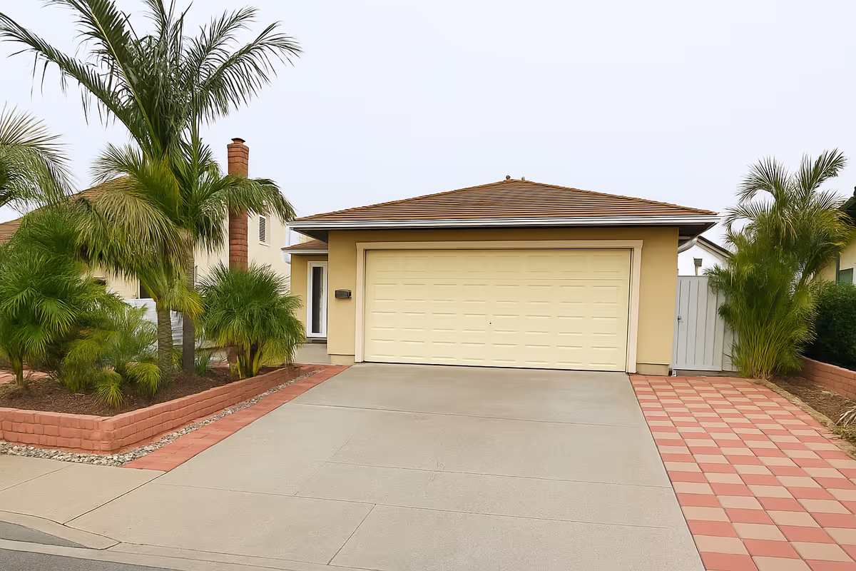 Front view of a beige single-story house with a two-car garage and palm trees.