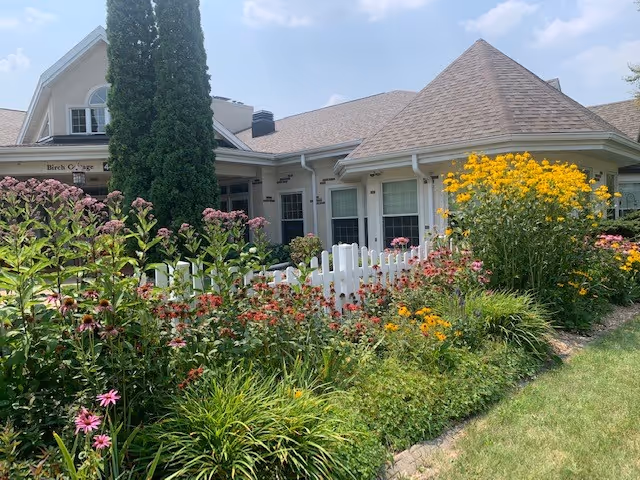 Front view of The Heritage & Peabody Manor with a white fence and colorful garden.