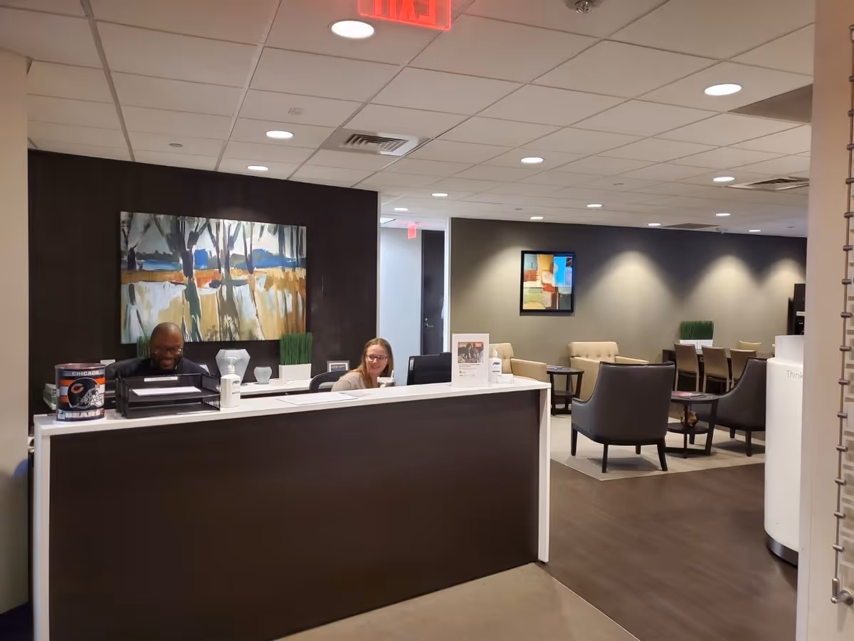 Reception desk with two staff members in a modern senior living lobby.