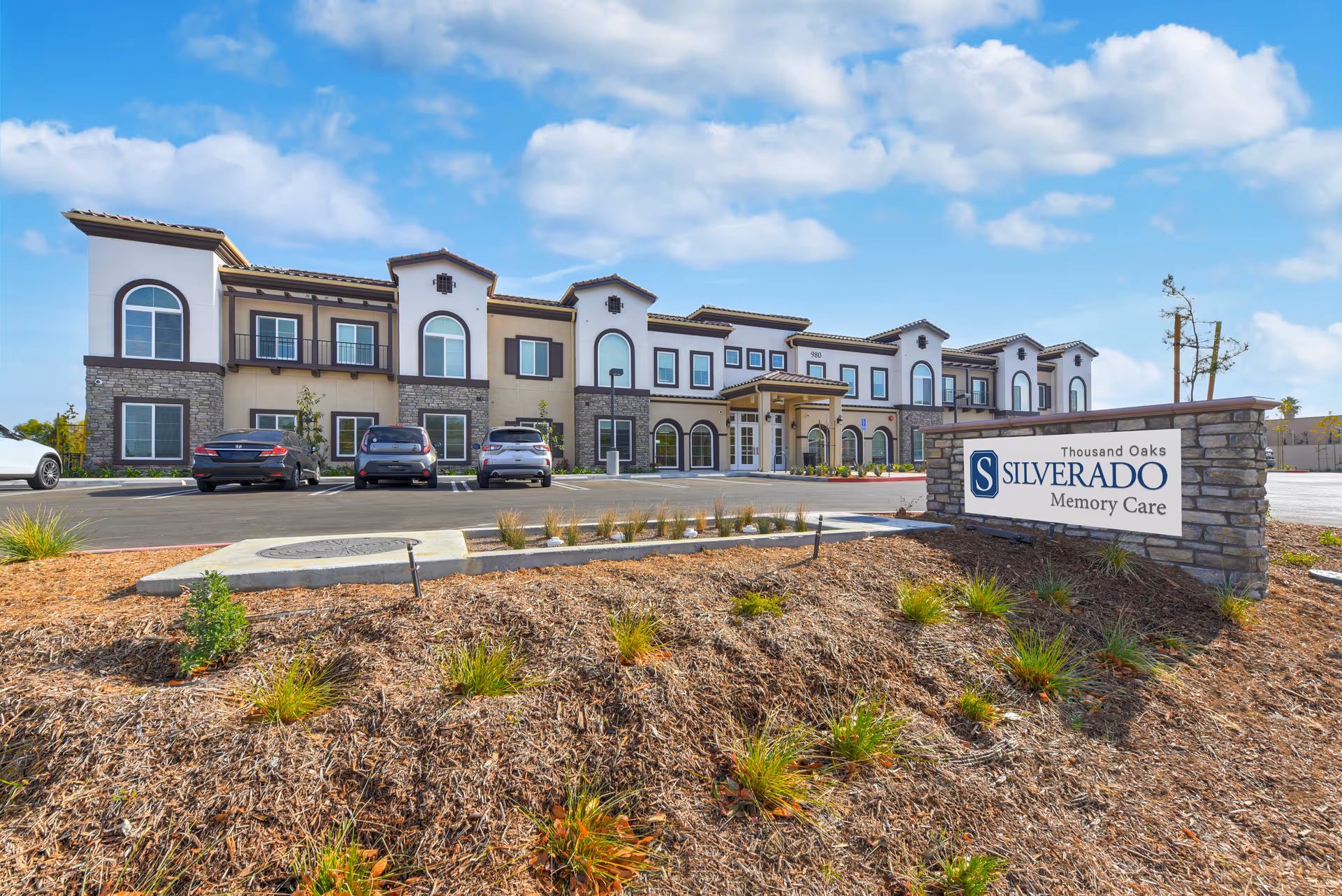 Exterior view of Silverado Thousand Oaks memory care facility with a stone sign and parked cars.