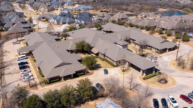 Aerial view of a single-story healthcare facility with a surrounding parking lot and nearby residential homes.