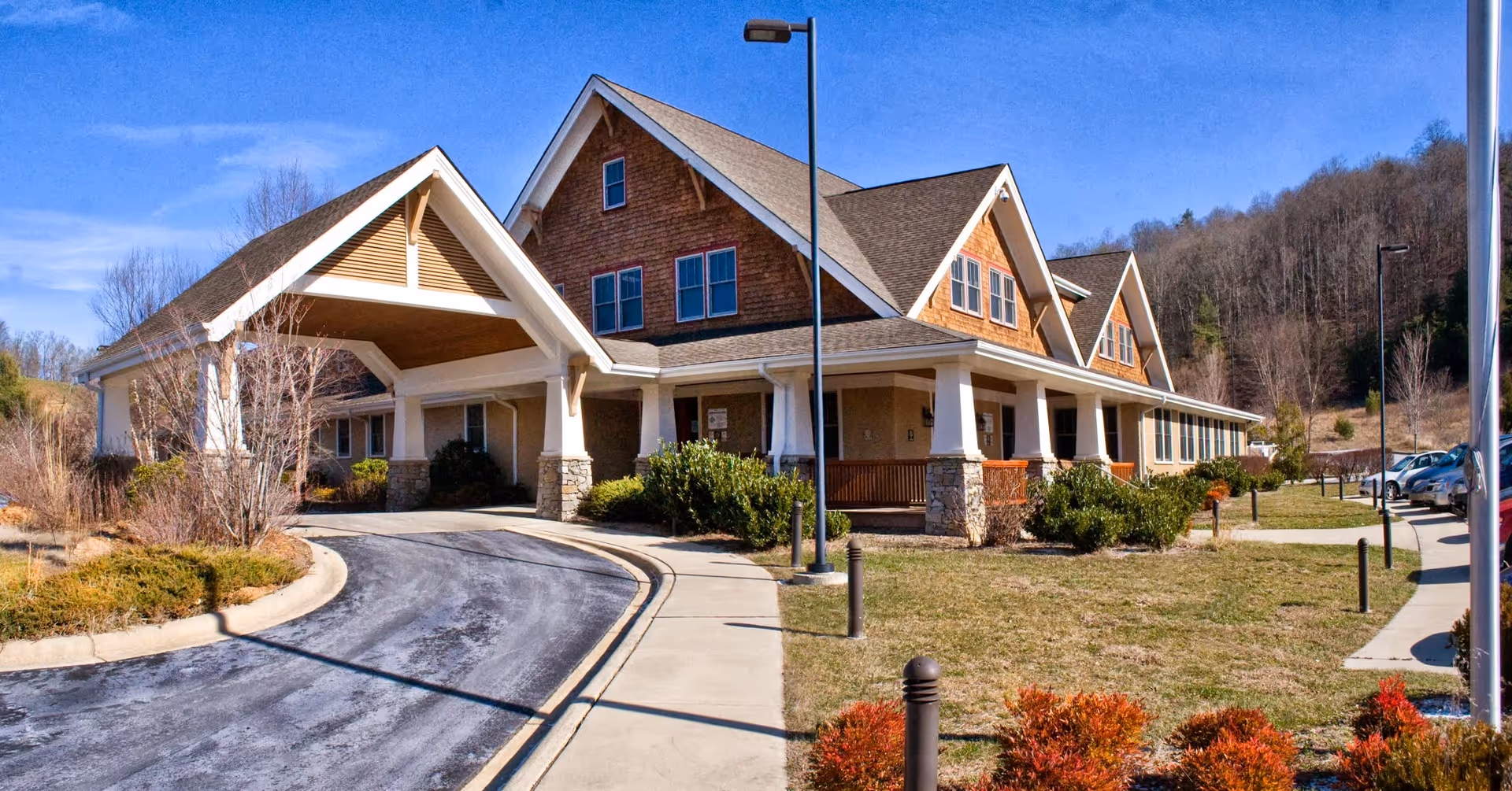 A spacious, modern senior living facility exterior with a curved driveway and landscaped entrance.
