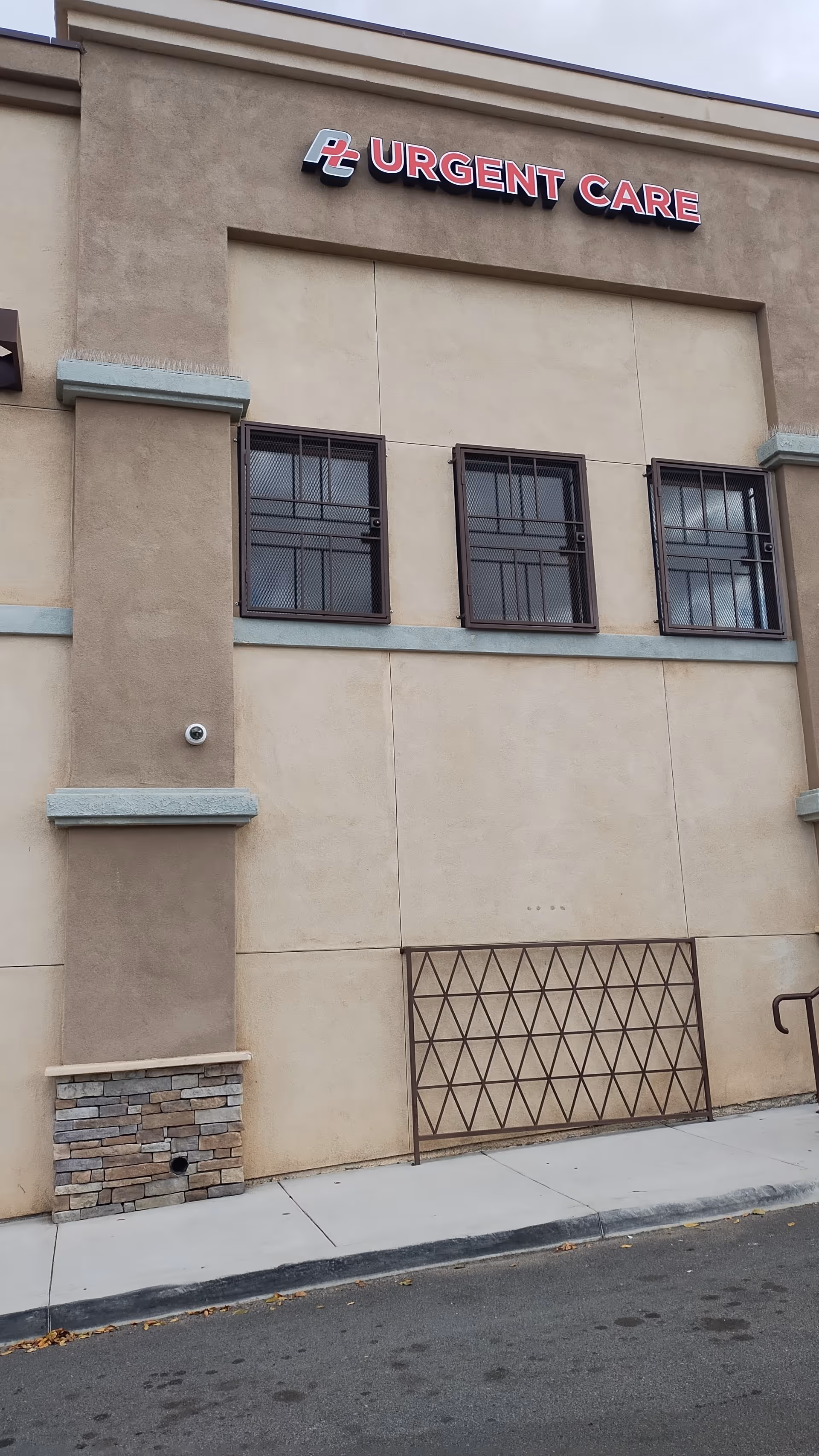 Front facade of Perris Urgent Care clinic with beige exterior and three barred windows.
