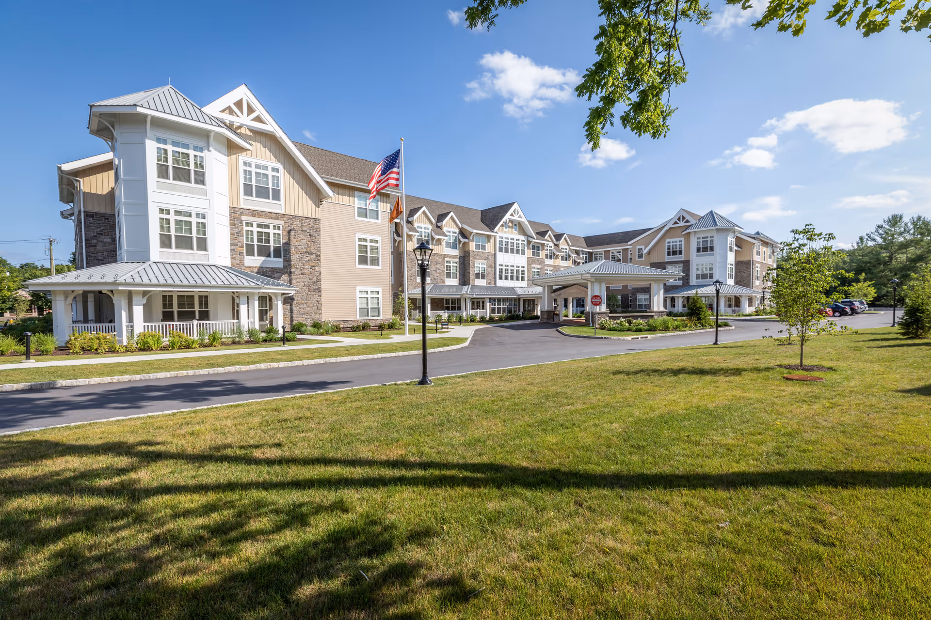 Exterior of Sunrise of Wilton senior living facility with lawn, driveway, and American flag
