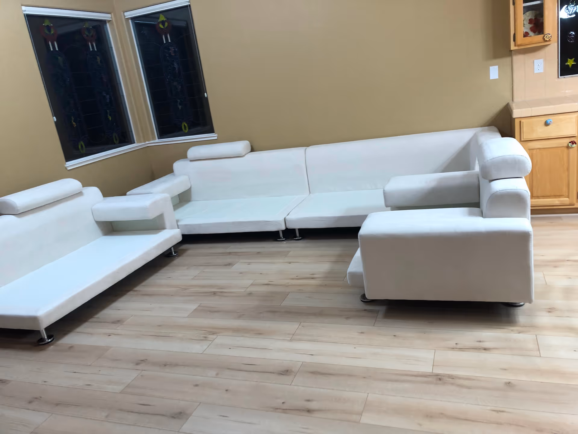White modular sofas form an L-shaped seating area in a bright living room with wood floors.