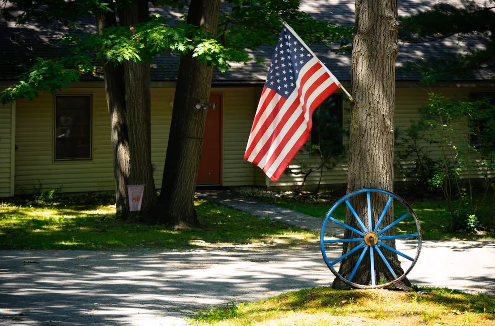 American flag by a tree in front of a beige assisted living facility.