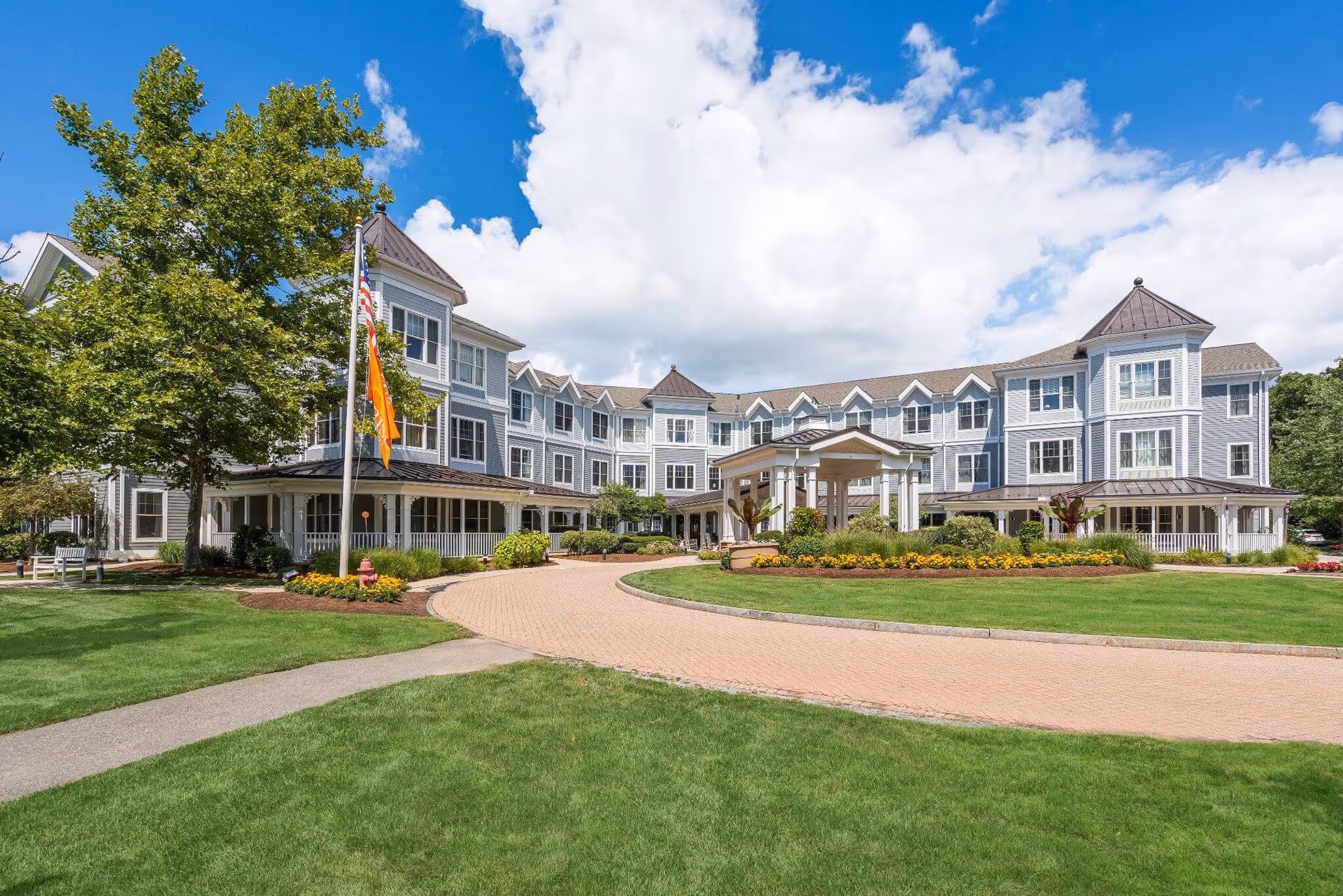 Exterior view of Sunrise of Burlington MA: blue-gray multi-wing senior living building with circular driveway.
