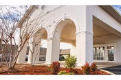 White building with arched entrance and covered porch at Prattville Health and Rehabilitation, LLC.
