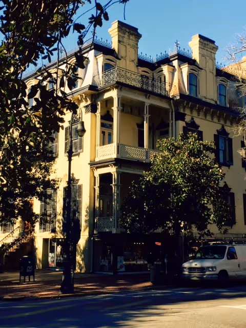 Exterior view of a beige, multi-story building with balconies on a city street.