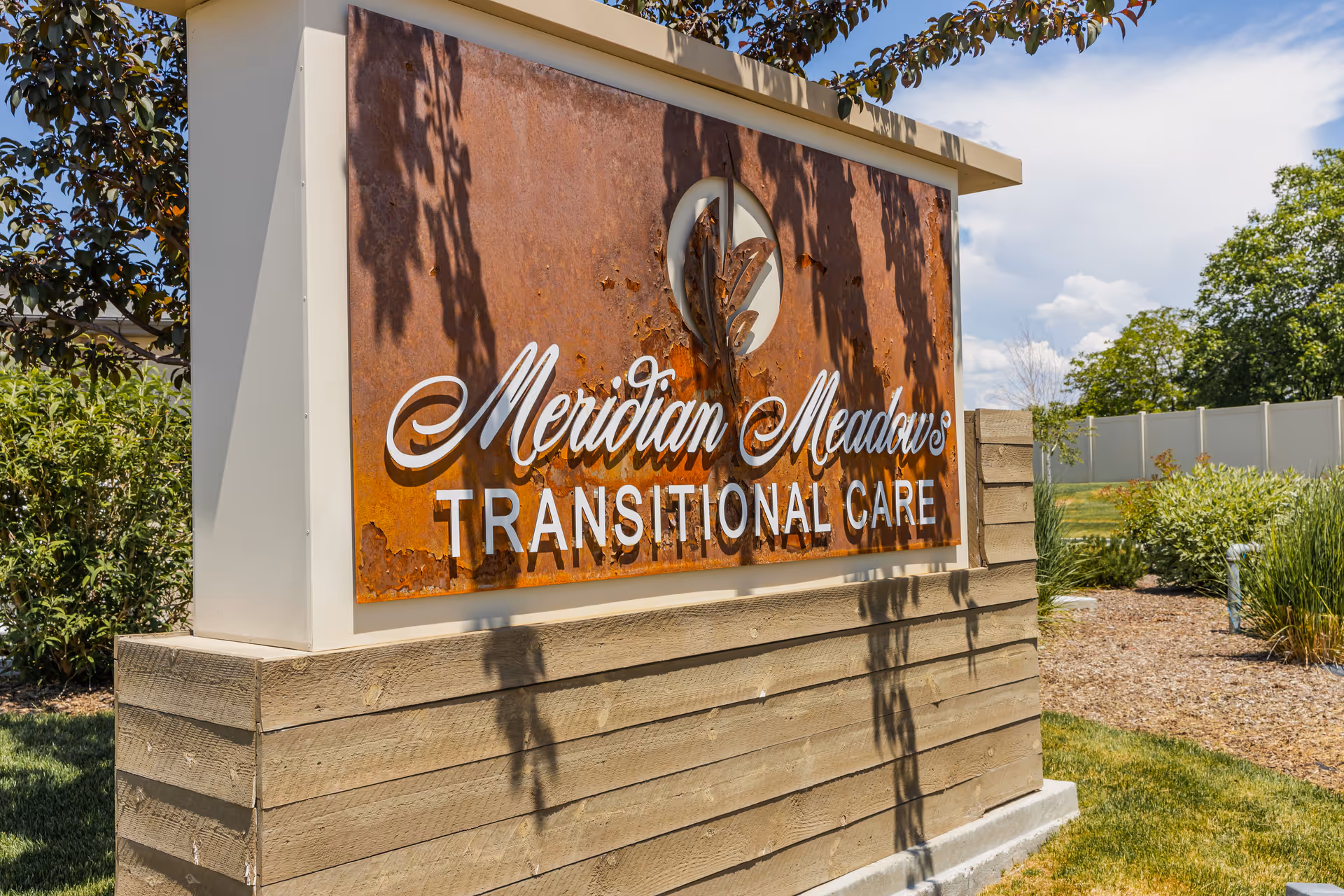A rusted metal sign reading Meridian Meadows Transitional Care on a wooden exterior structure.