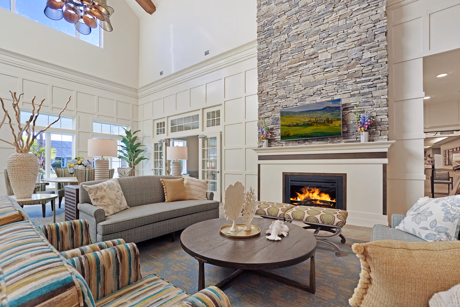 Spacious living room with a stone fireplace, high ceilings, and plush seating.
