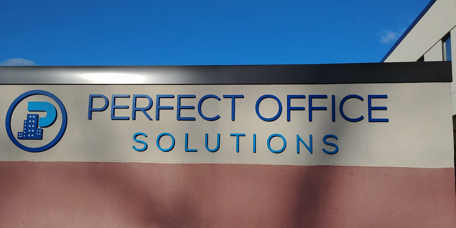 Exterior view of a building with a large 'PERFECT OFFICE SOLUTIONS' sign