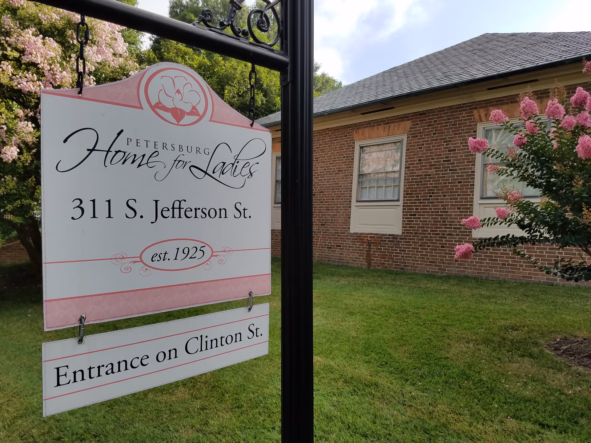 Exterior view of Petersburg Home for Ladies sign beside a brick building and pink flowering bush
